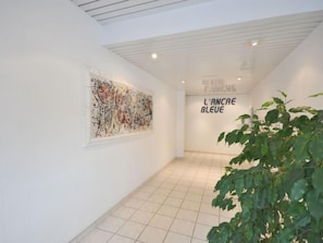 A hallway with a large abstract painting on the left and a sign reading "L'ANCARE BLEUE" on the right.