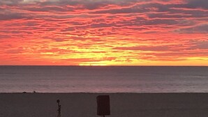 Atardecer sobre el océano con una playa al frente.