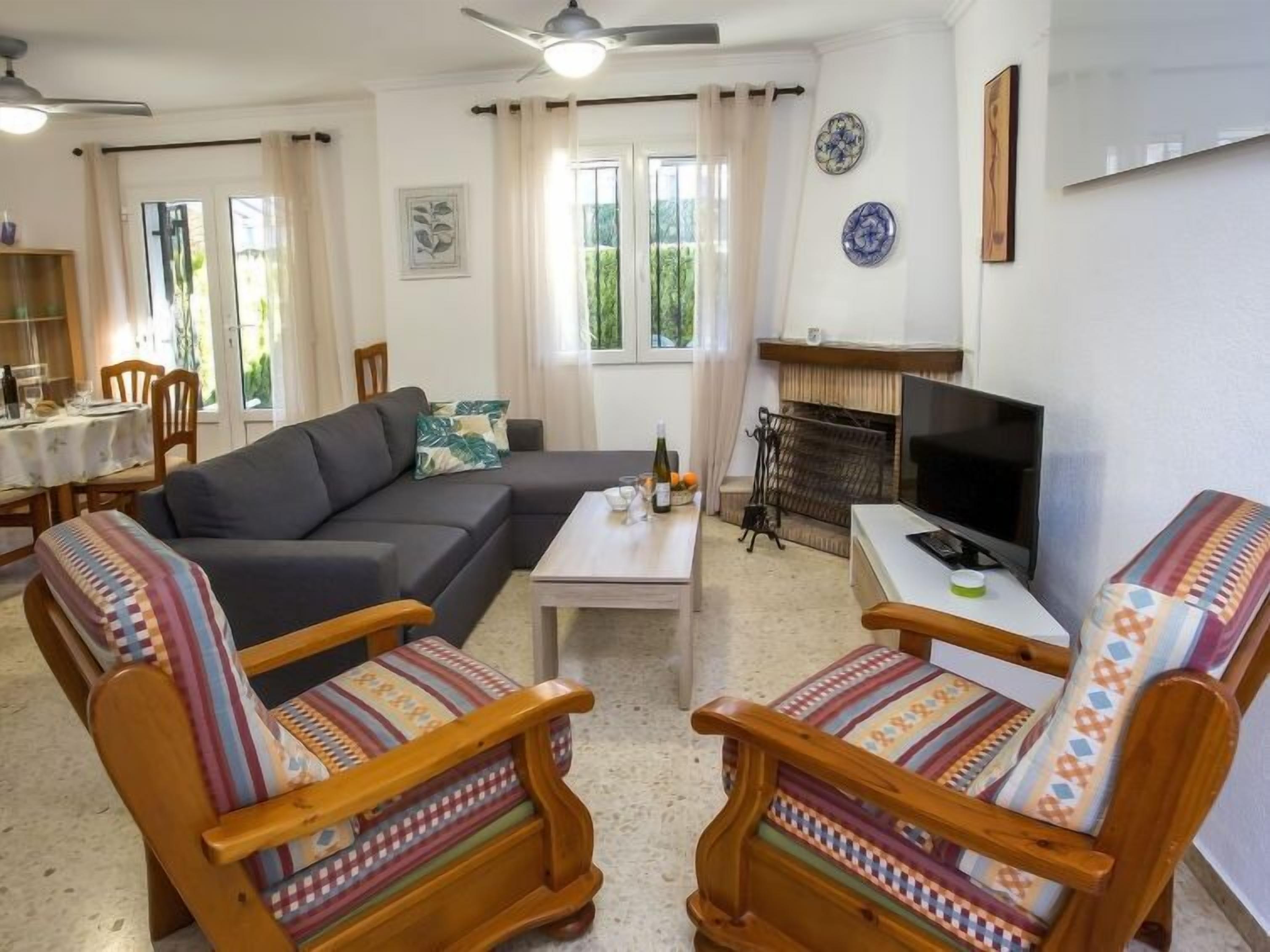 Una sala de estar con un sofá, dos sillas de madera, una mesa de centro, un televisor y una chimenea.