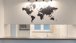 A modern kitchen with a world map wall art, a window with a view, and three unique black and white vases on the counter. - Ocean with parking by Interhome (Bredene)