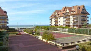 A residential building with multiple balconies, a tennis court, and a view of the sea. - Les Normandières by Interhome (Cabourg)