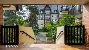 Un cancello conduce a una zona residenziale, con un vialetto lastricato che porta a un edificio con numerosi balconi.