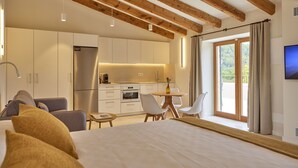 Une chambre d’hôtel moderne dotée d’un grand lit, d’un coin repas, d’une cuisine et d’un balcon avec télévision.