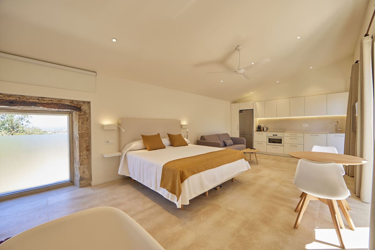 A modern bedroom with a large bed, a bedside table, and a view of the outdoors.
