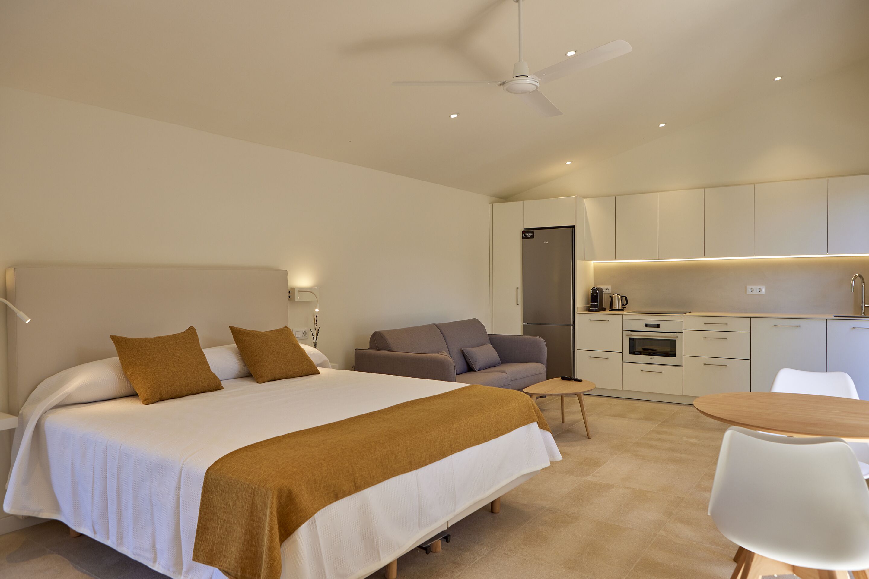 Una habitación de hotel moderna con una cama grande, un sofá, una mesa de comedor y una kitchenette.