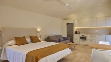 Una habitación de hotel moderna con una cama grande, un sofá, una mesa de comedor y una kitchenette.