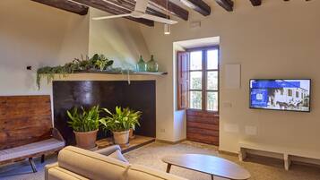 A cozy living room with a fireplace, sofas, a coffee table, and a TV mounted on the wall.