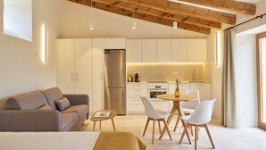 Une cuisine moderne avec des meubles blancs, un réfrigérateur en acier inoxydable et un coin repas comprenant une table ronde et des chaises blanches.