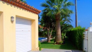 Ein Wohnhaus mit Garage, befestigter Auffahrt und einem gepflegten Rasen mit Palmen.