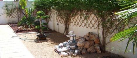 A garden with a variety of plants, a small rock garden, and a lattice wall.