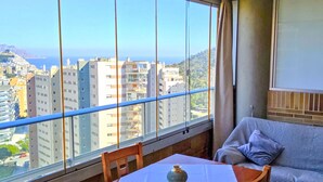 Un balcon avec une table et des chaises, un canapé et une vue sur le paysage urbain et la côte.