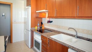 Une cuisine avec des meubles en bois, un évier blanc et une cuisinière.