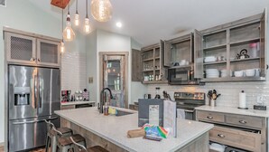 A modern kitchen with stainless steel appliances, wooden cabinets, and a central island with bar stools.