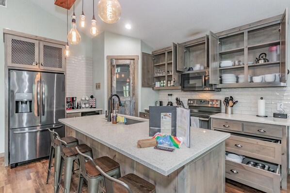 Een moderne keuken met roestvrijstalen apparatuur, houten kastjes en een centraal eiland met barstoelen.