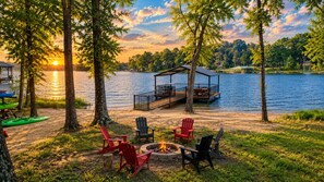 A lakeside deck with outdoor seating and a fire pit.