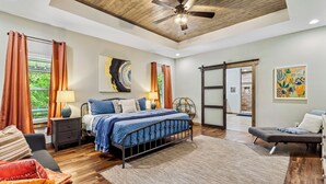 A modern bedroom with a bed, bedside tables, a sofa, and a ceiling fan.