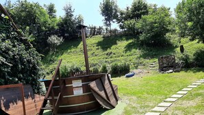 A wooden boat on a grassy slope with a wooden ramp leading up to it.