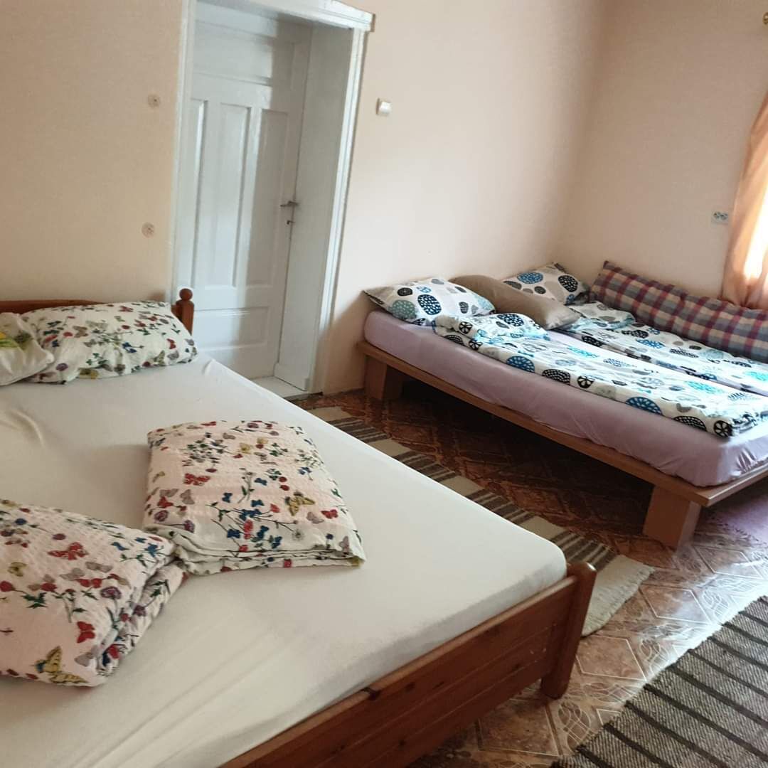 Een slaapkamer met twee bedden, waarvan één met bloemenbeddengoed en de ander met een gestreept bed.