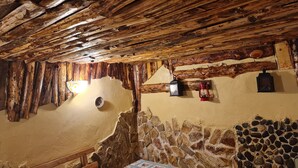 A rustic room with exposed wooden beams, a stone wall, and a wooden bench. - House of Rei With Hot Tube (Ocolis)