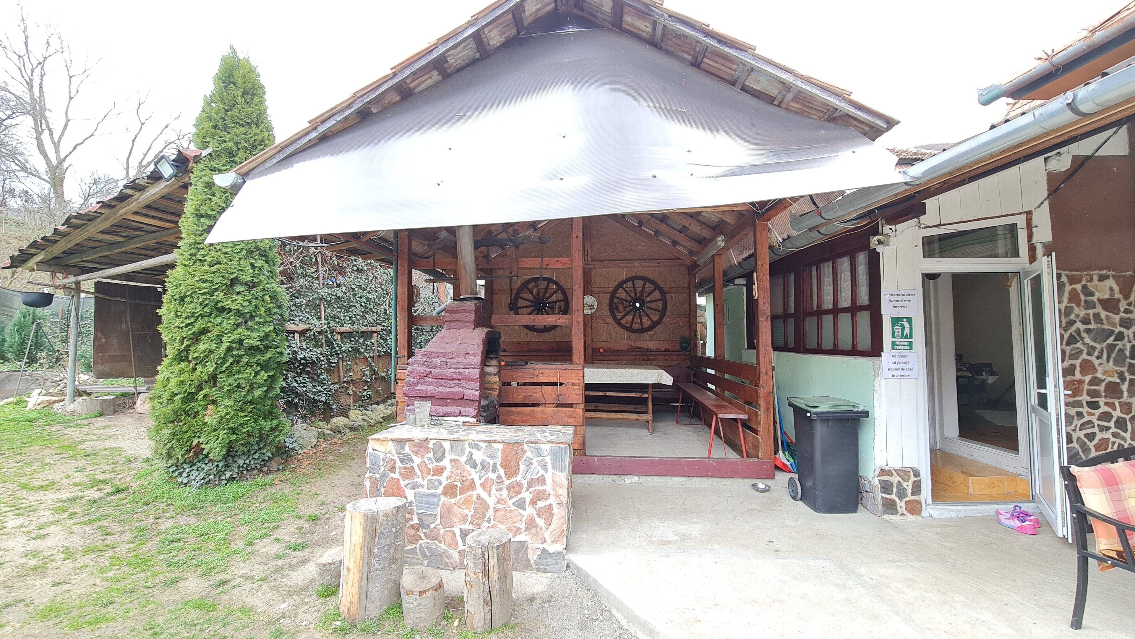 Een rustiek gebouw met een stenen muur, houten banken en een overdekt terras.