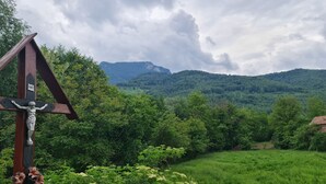 A wooden cross with a crucifix, surrounded by lush greenery and mountains in the background. - House of Rei With Hot Tube (Ocolis)