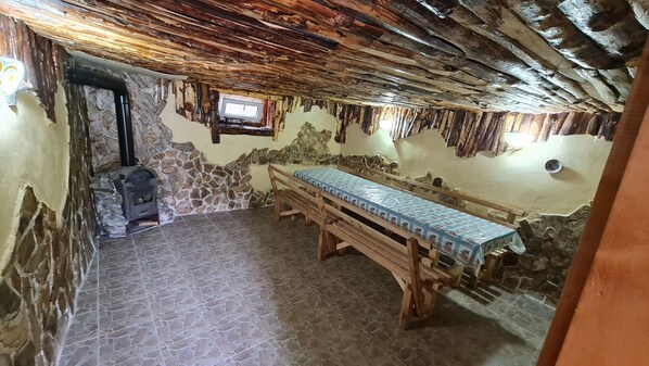 Una habitación rústica con pared de piedra, un banco de madera y chimenea.