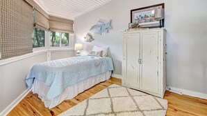 Ein Schlafzimmer mit einem Bett, einem Nachttisch, einer Lampe, einem Kleiderschrank und einem Fenster mit Jalousien.