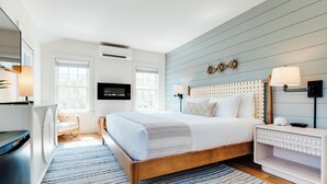 Ein modernes Schlafzimmer mit einem Holzbett, einem an der Wand befestigten Fernseher und einem Nachttisch mit einer Lampe.