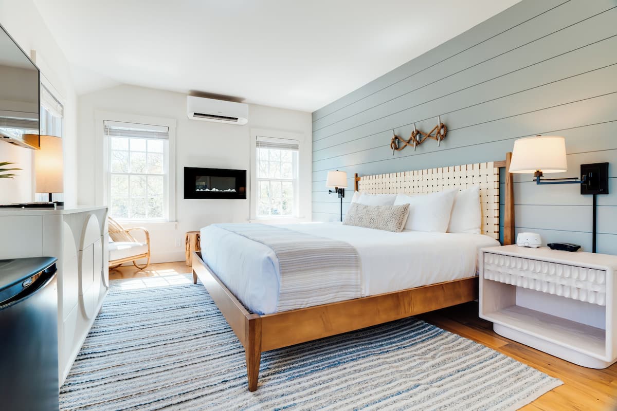A modern bedroom with a wooden bed, a TV mounted on the wall, and a bedside table with a lamp.