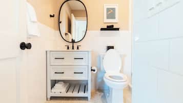 A bathroom with a white sink, a toilet, a mirror, and a towel rack.