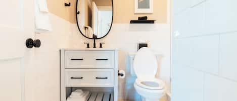 A bathroom with a white sink, a toilet, a mirror, and a towel rack.