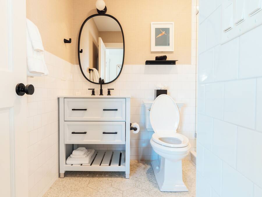 A bathroom with a white sink, a toilet, a mirror, and a towel rack.