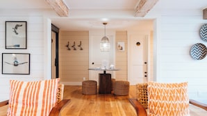 Ein Zimmer mit Holzboden, einem runden Tisch mit weißer Tischplatte und zwei Korbstühlen.