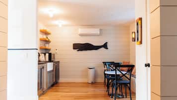A compact kitchen with wooden flooring, white cabinets, a microwave, and a hanging fish sculpture.