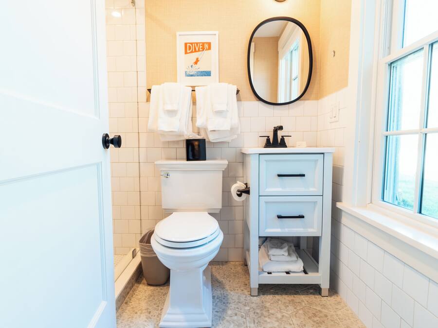 Un baño con inodoro, lavamanos, espejo y ventana.