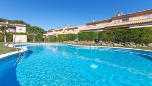 A clear blue swimming pool surrounded by a landscaped area with a building in the background. - Bon Retorn by Interhome (L'Escala)