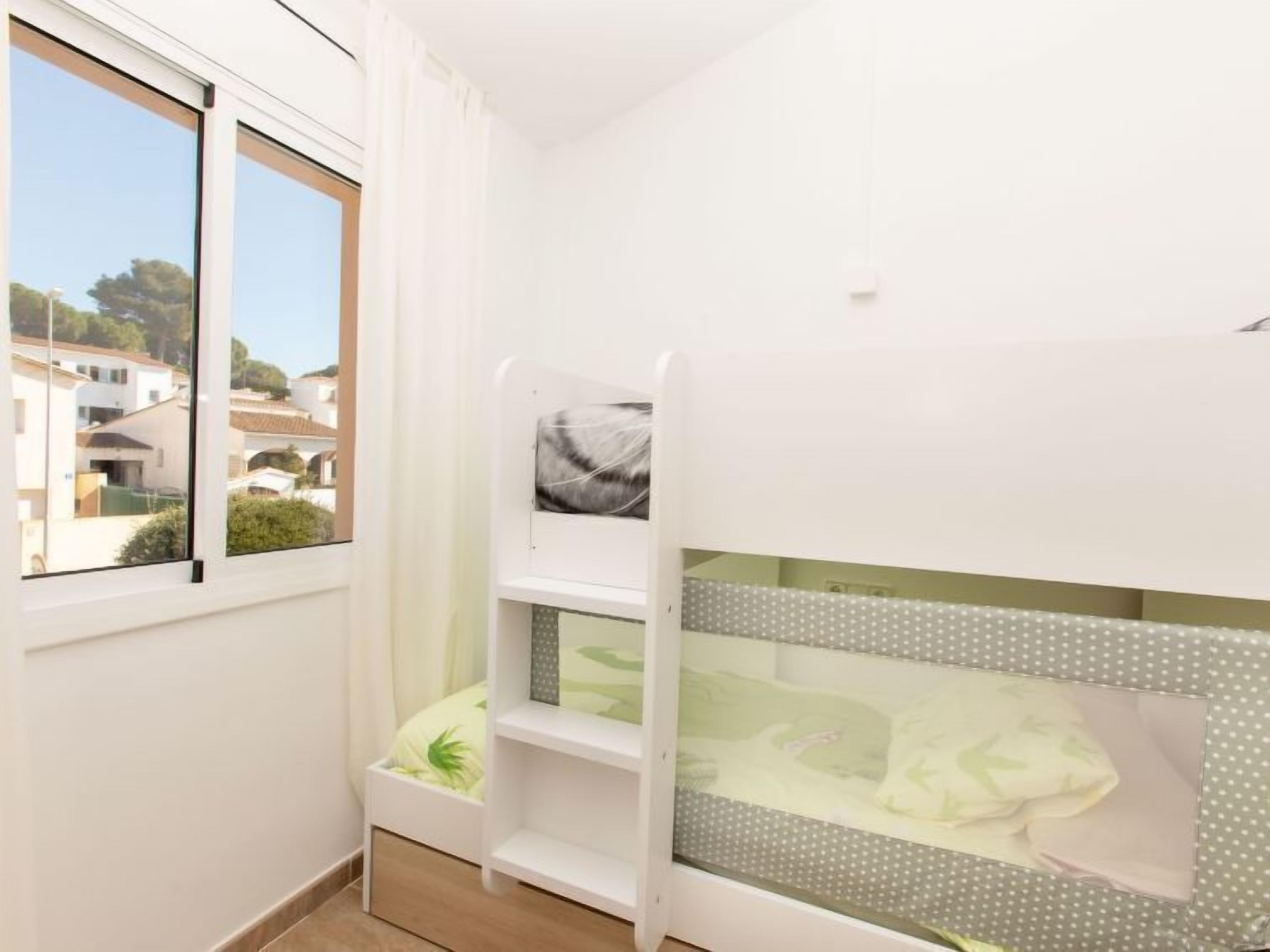 Llits superposats infantils amb vista a una zona residencial a través d'una finestra.