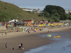 A beach with colorful buildings, a sandy shore, and a few people.