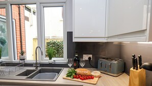 Eine moderne Küche mit Spüle, Toaster und Schneidebrett mit Tomaten und Brot.