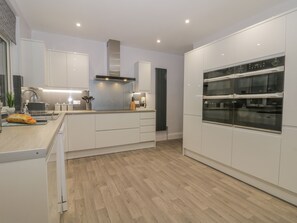 A modern kitchen with white cabinets, a central island, and built-in ovens.