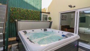 Ein Whirlpool in einem Garten mit einem grünen Zaun und einem kleinen Garten.