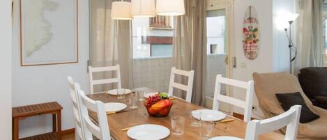 A dining area with a wooden table, white chairs, and hanging pendant lights.