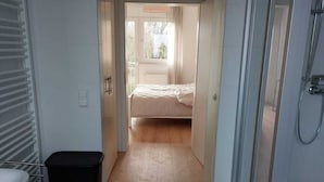 A modern bathroom with a shower, a toilet, and a sink. There is a small trash bin and a black rug on the floor. - Fewo Provinzperle - newly designed - an ideal starting point for your tours (Freckenfeld)