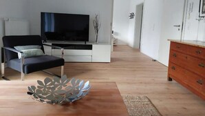 A modern living room with a black sofa, a flat-screen TV, and a wooden coffee table. - Fewo Provinzperle - newly designed - an ideal starting point for your tours (Freckenfeld)