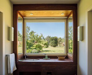 Une salle de bain avec une grande fenêtre, un plafond en bois et un lavabo avec une serviette.