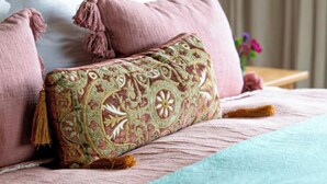 A bed with patterned pillows and a decorative throw.