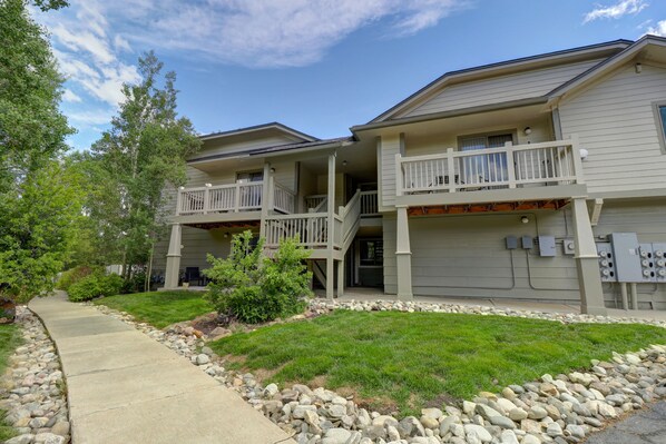A two-story residential building with a covered front porch, a stone pathway, and a well-maintained lawn.