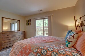 A bedroom with a large bed, a dresser, a window with curtains, and a ceiling light.
