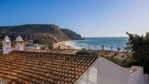 A coastal view with a beach, ocean, and a hill in the background. - Waterside Village Townhouse (Luz)