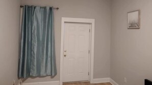 A room with a white door, a blue curtain, and a framed picture on the wall. - lovely relaxing room with hight speed internet , neflix with a independent entry (Goose Creek)